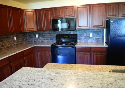 Kitchen with red wood cabinets and black appliances at The Reserve at Manada Hill in Hershey PA